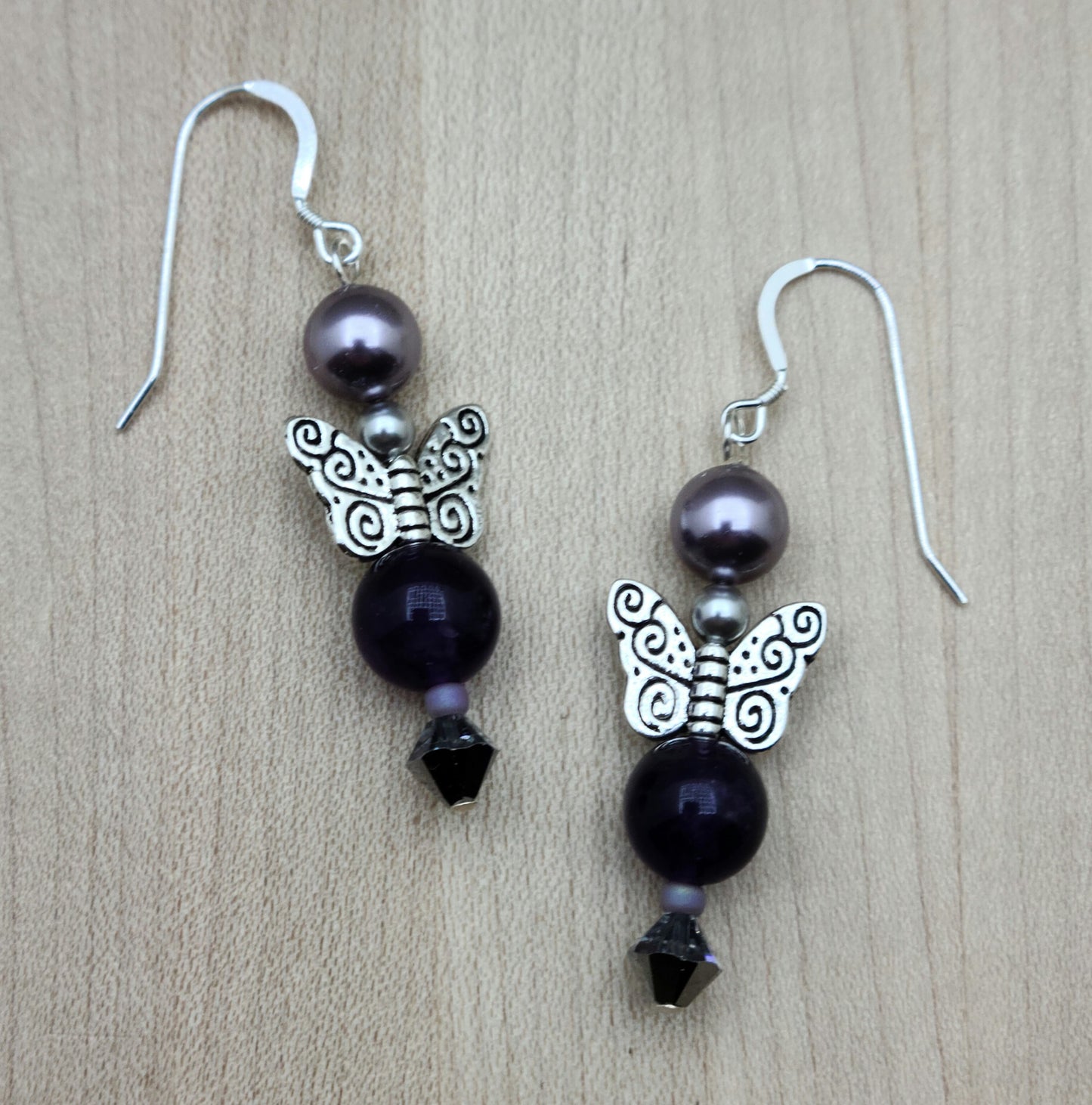 Amethyst quartz, crystals, & crystal pearls highlight fancy pewter butterflies in the earrings with sterling silver fish hook ear wires.