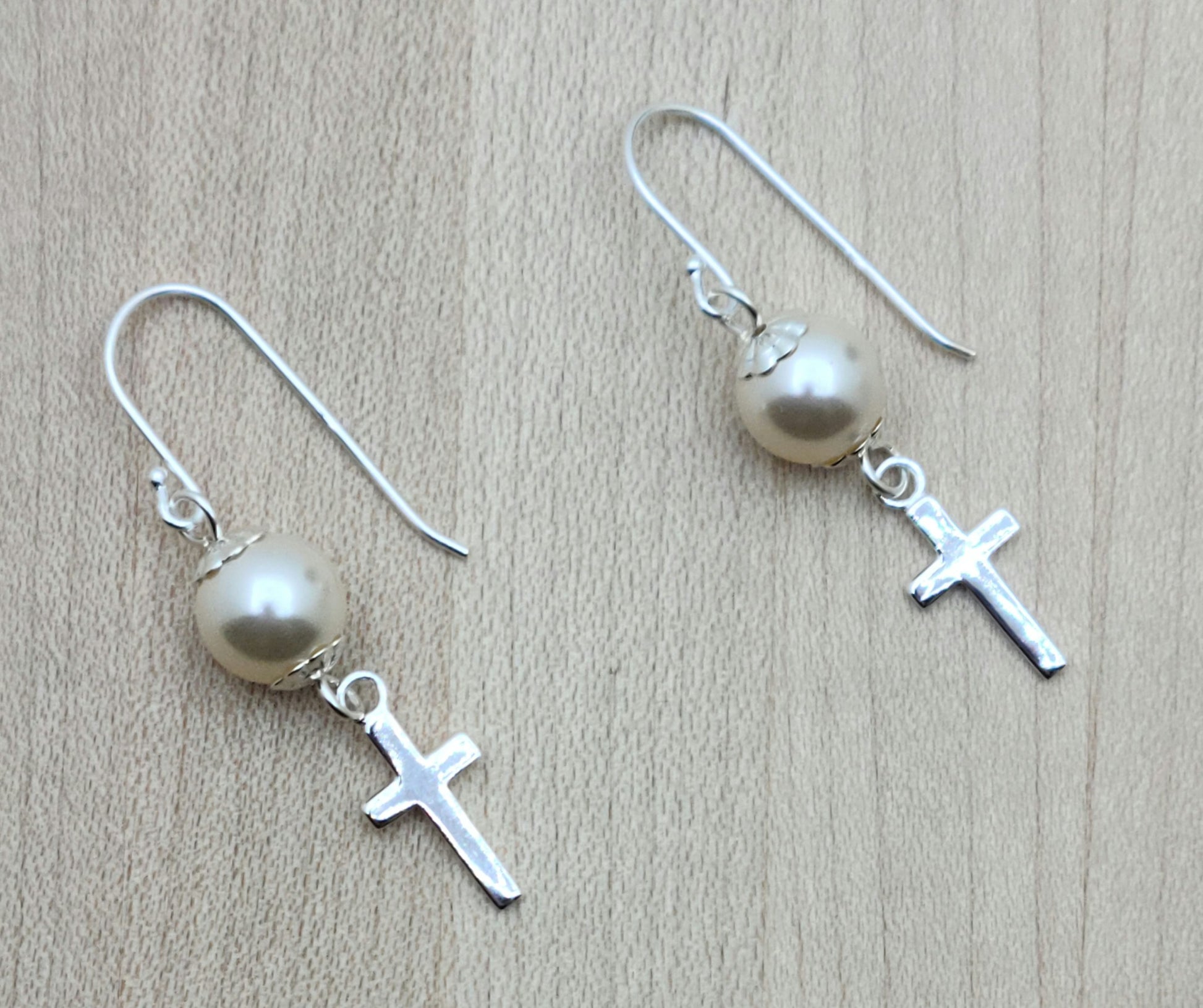 Dainty sterling silver cross dangle from creamrose crystal pearls on sterling silver  fish hook ear wires.
