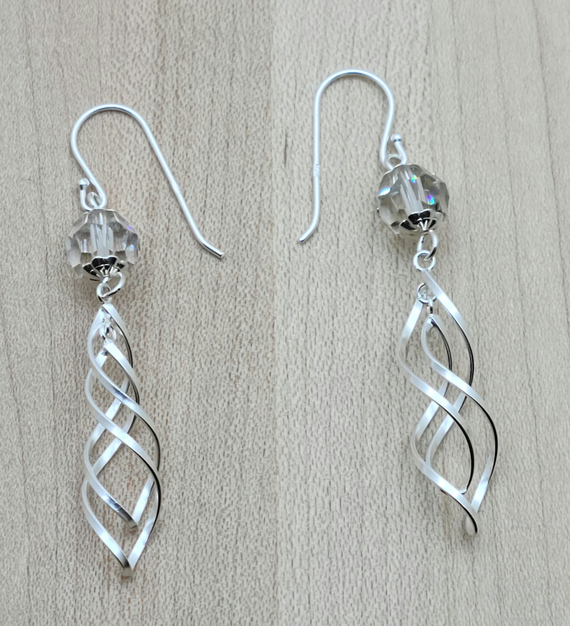 a large silver shadow crystal hosts double sterling silver spirals & the combo dangles from sterling silver fish hook ear wires. Very chic!