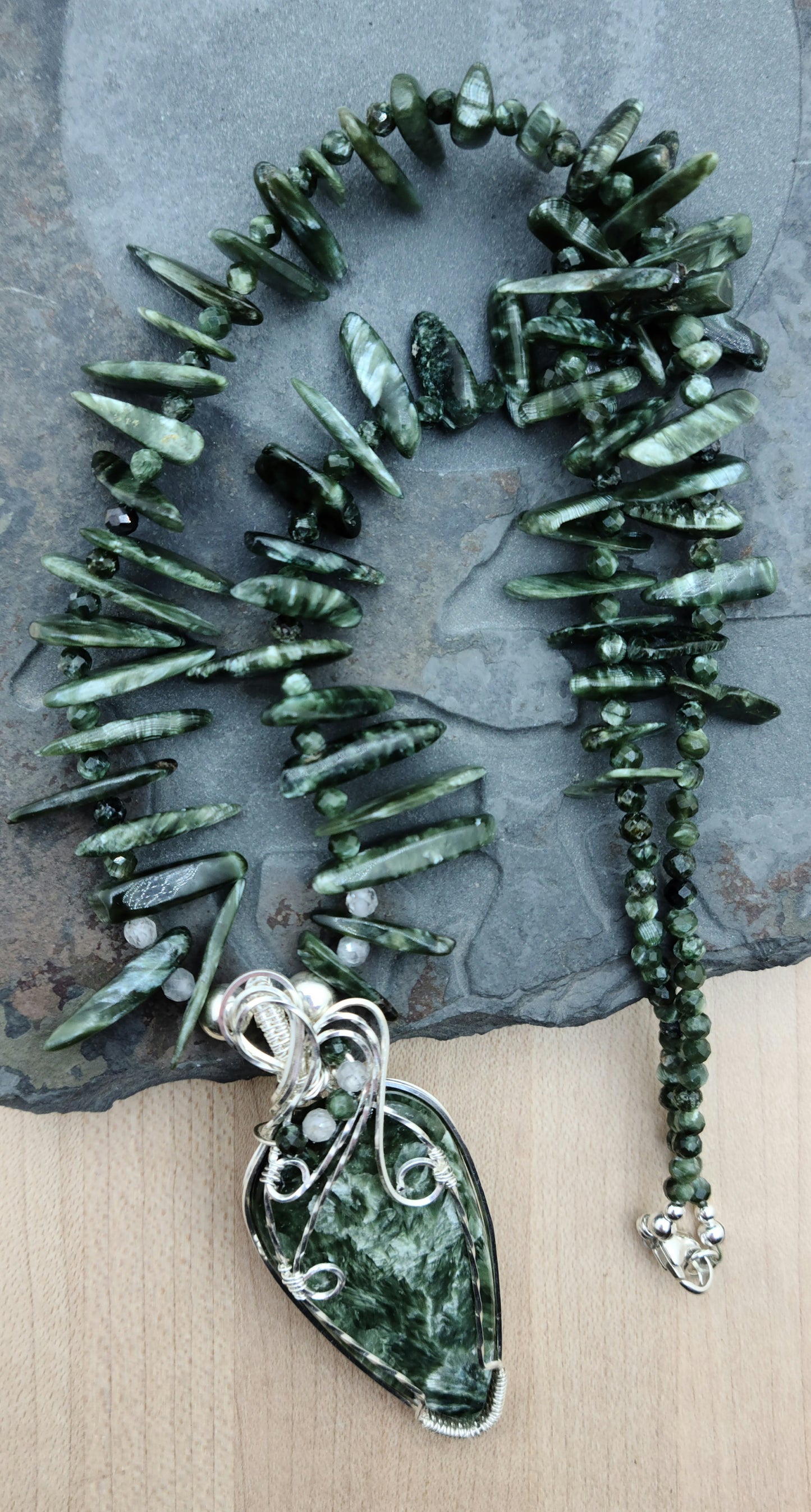 a seraphinite cabochon is framed in woven silver filled wire and hangs from necklace of seraphinte freeform spikes.