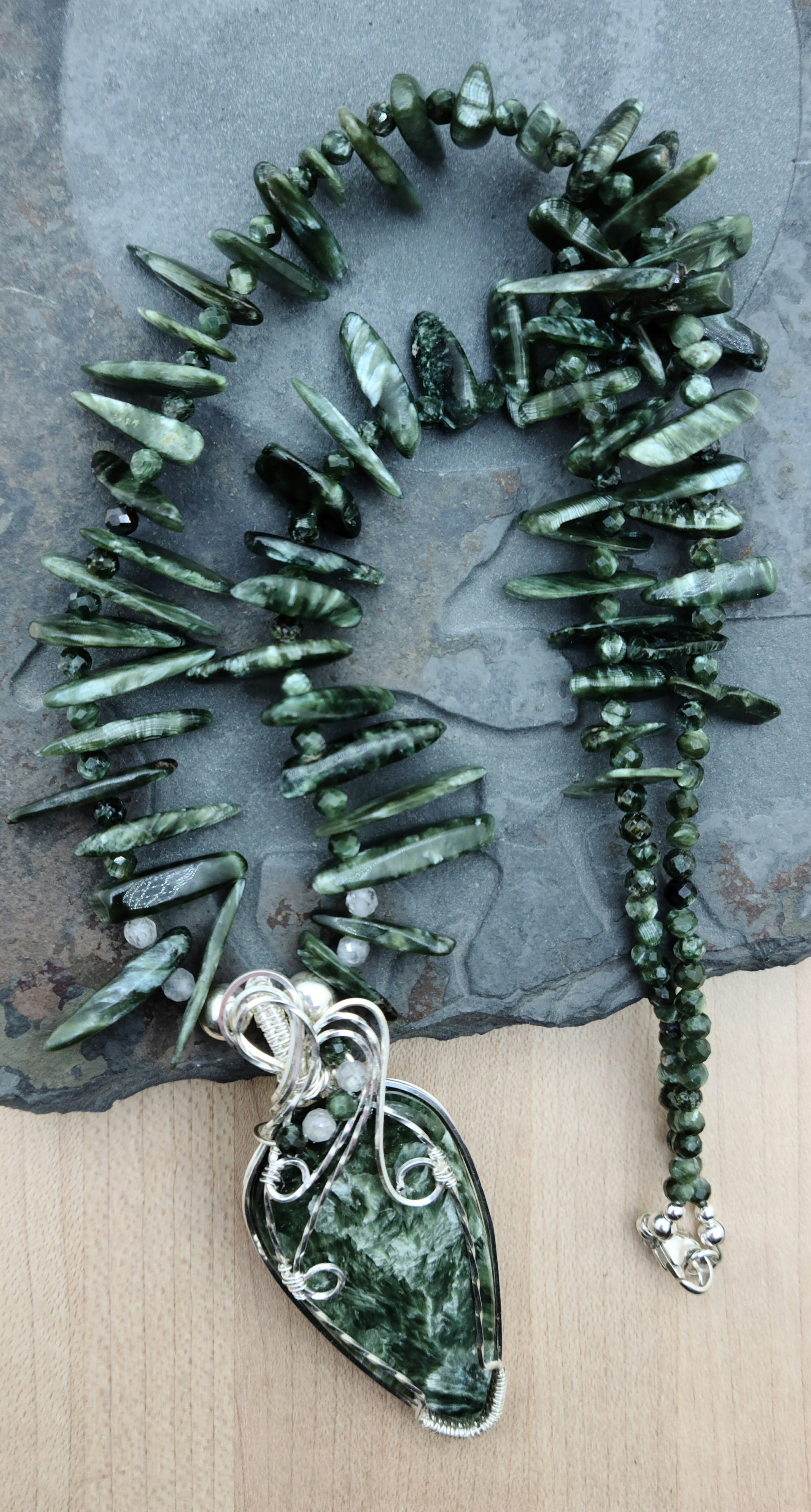 a seraphinite cabochon is framed in woven silver filled wire and hangs from necklace of seraphinte freeform spikes.