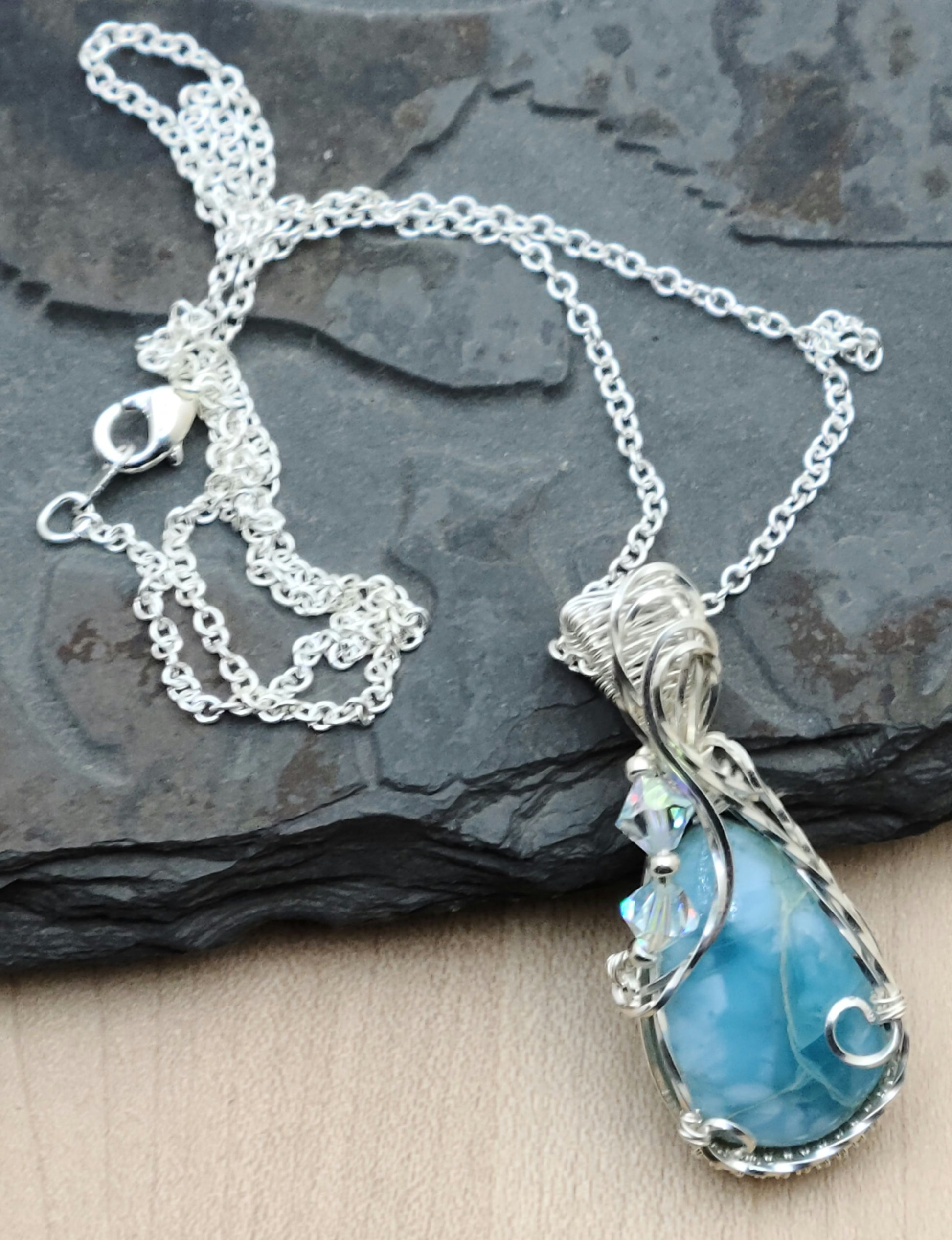 The frame to this beautiful, sky blue larimar stone was woven from silver filled wire and adorned with translucent crystals. 