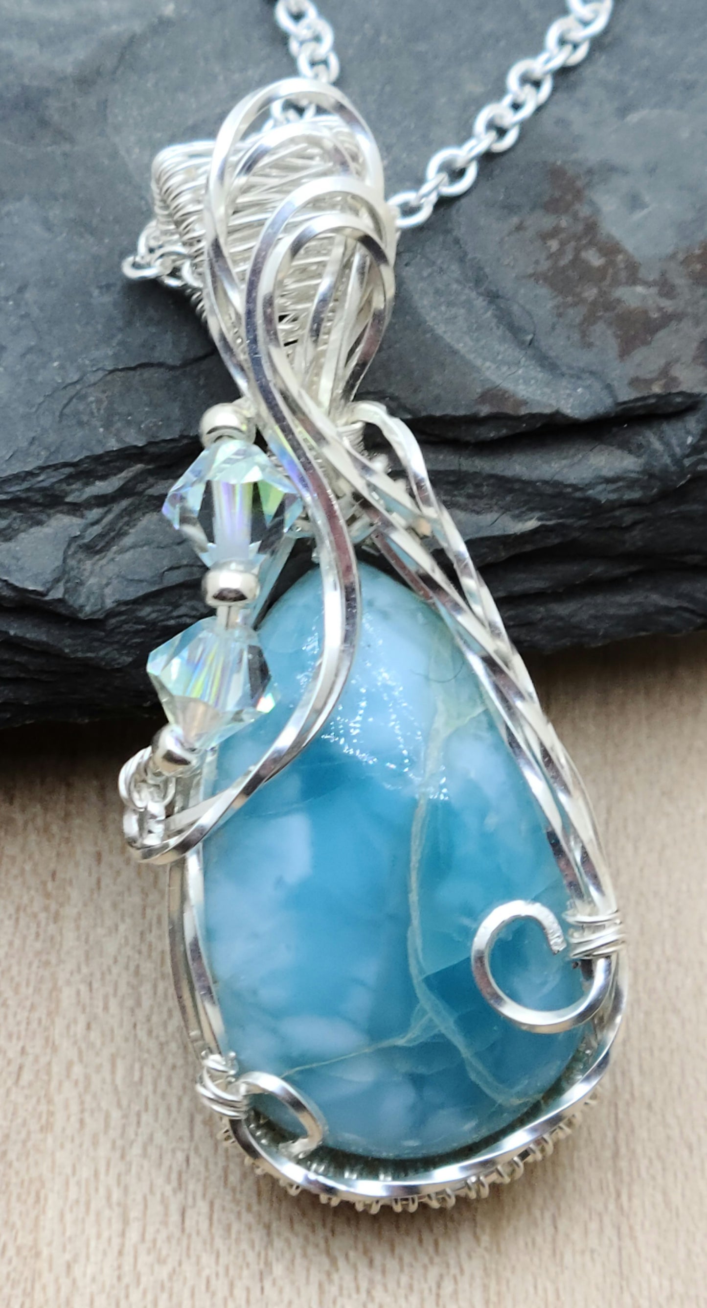 The frame to this beautiful, sky blue larimar stone was woven from silver filled wire and adorned with translucent crystals. 