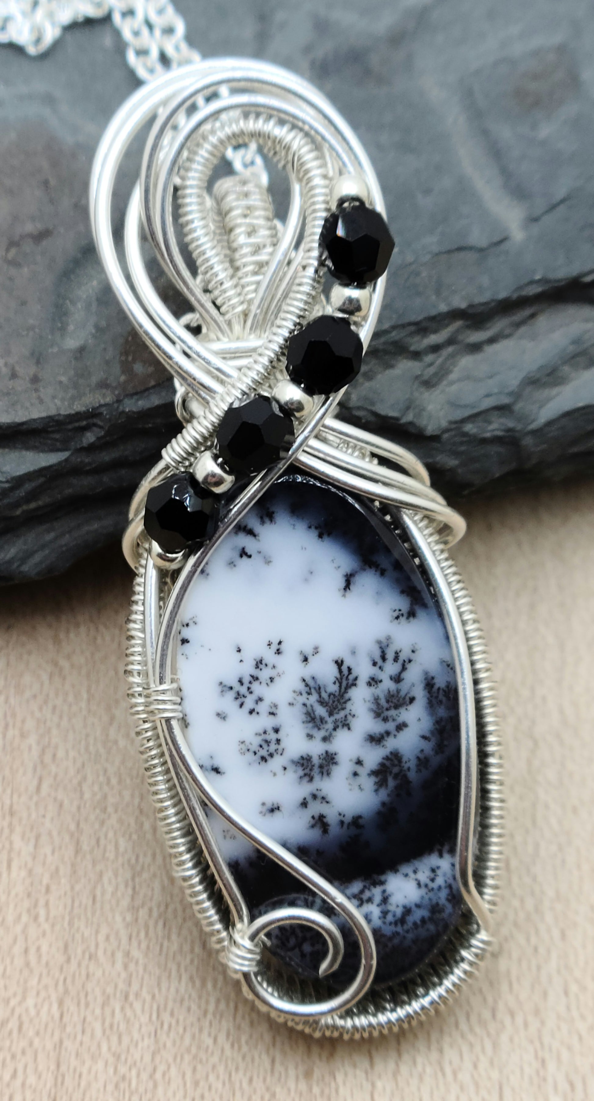This fascinating dendrite stone has a scenic look to it. I framed it with woven silver filled wire and adorned it with tiny crystals