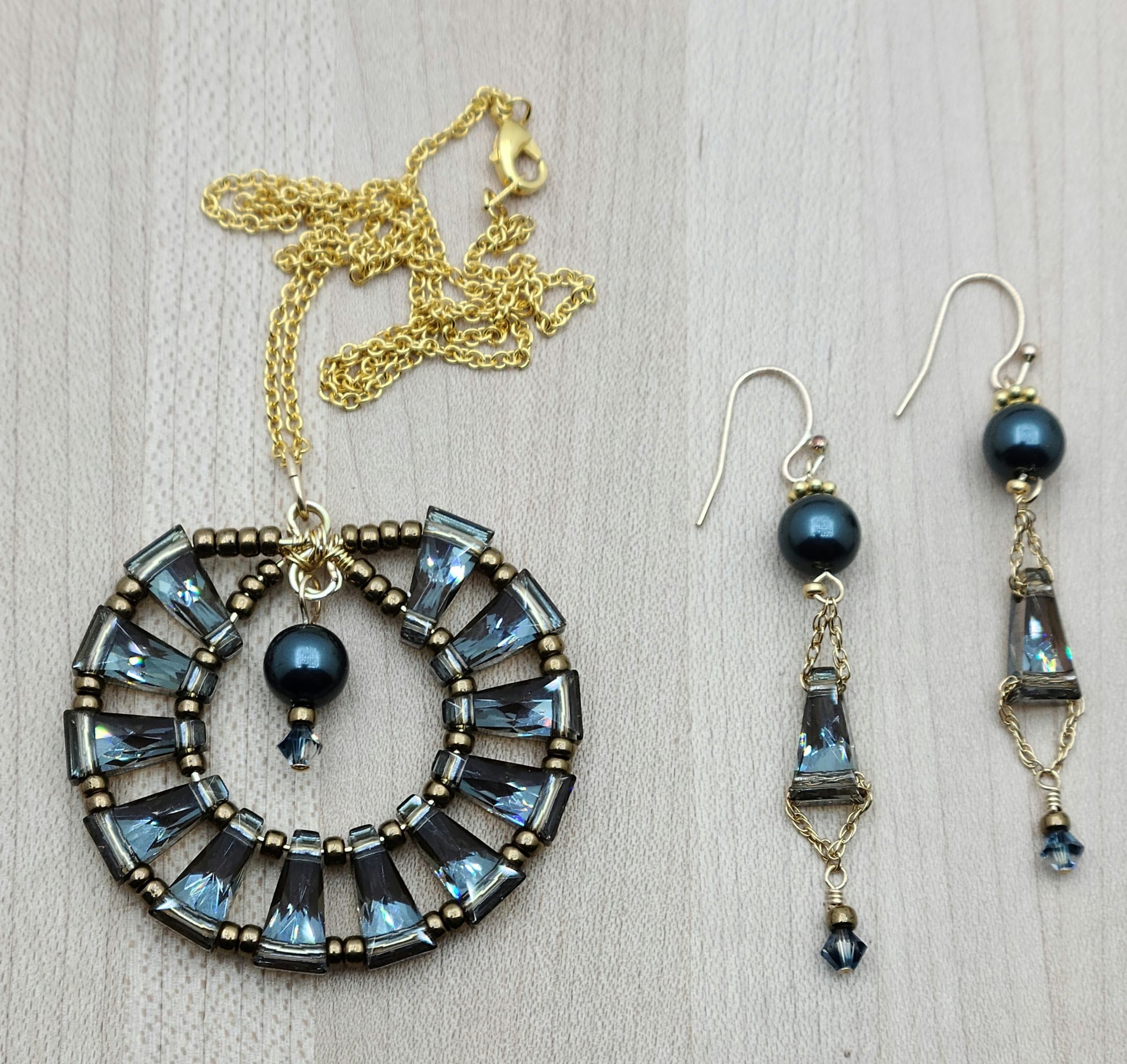 A gorgeous 'medallion' of blue back by bronze keyhole crystals circle up for a unique and flashy pedant! The earrings feature the same elements.