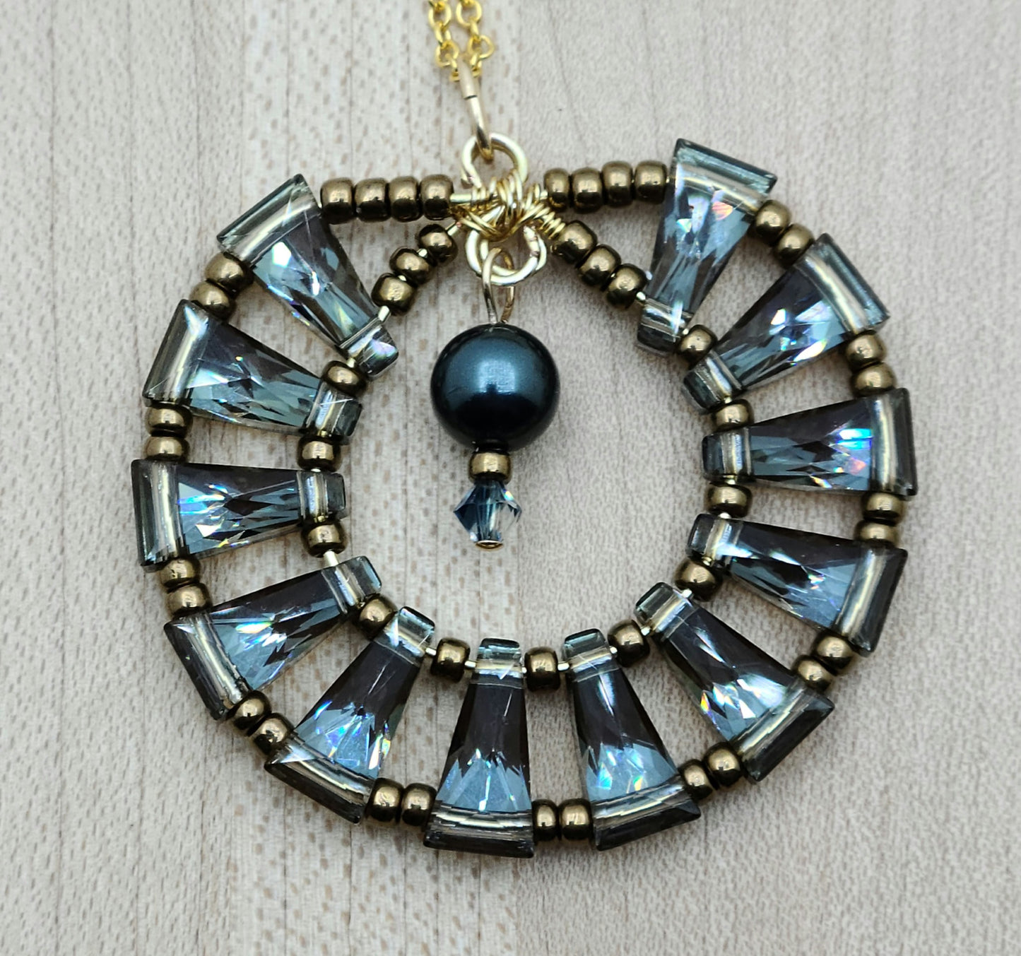 A gorgeous 'medallion' of blue back by bronze keyhole crystals circle up for a unique and flashy pedant!