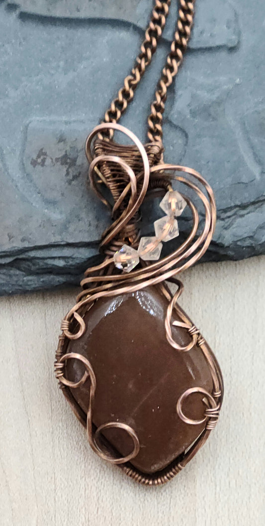 Antiqued copper woven wire creates a frame that allows this lovely peach moonstone to shine!