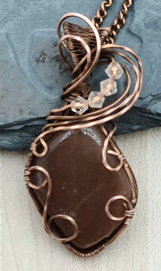 Antiqued copper woven wire creates a frame that allows this lovely peach moonstone to shine!