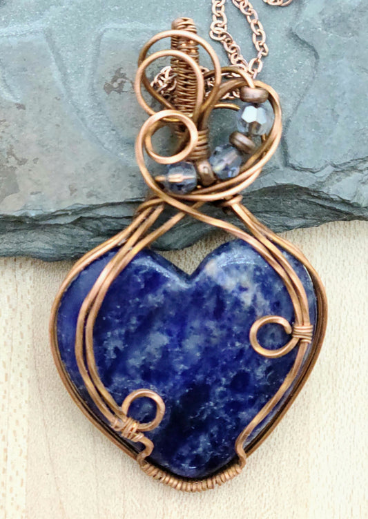 This delightful blue sodalite heart pendant is your ticket to speaking with confidence and creativity! Wrapped in warm antiqued copper wire, the Poet's Stone activates your throat chakra to help you express yourself authentically.