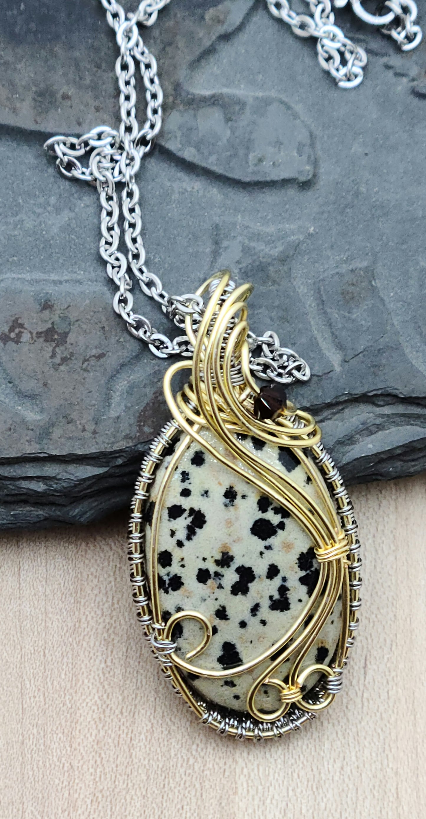 Sprinkle some serious joy into your day with this delightful dalmatian jasper pendant with gold & titanium hued woven wire frame!