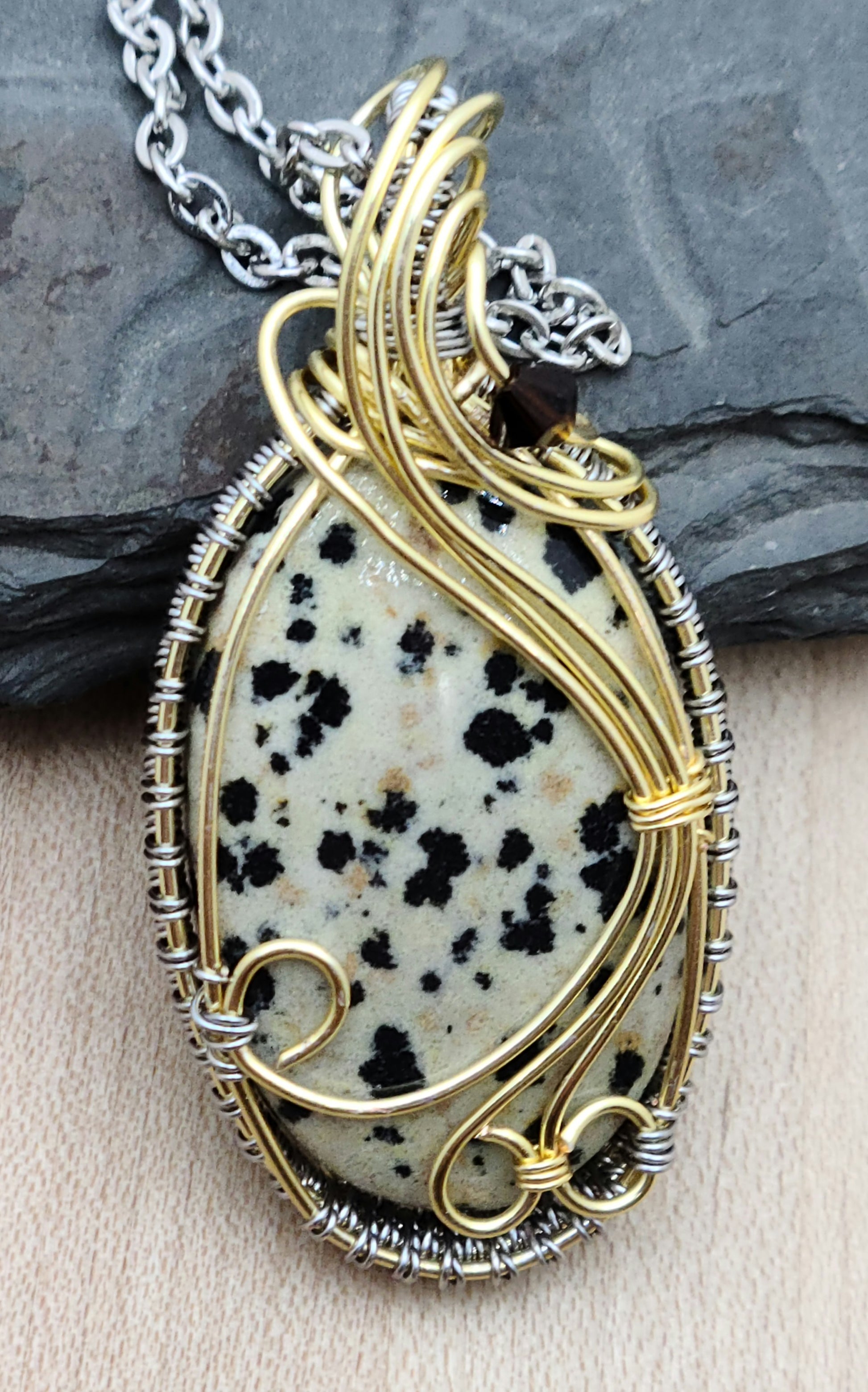 Sprinkle some serious joy into your day with this delightful dalmatian jasper pendant with gold & titanium hued woven wire frame!
