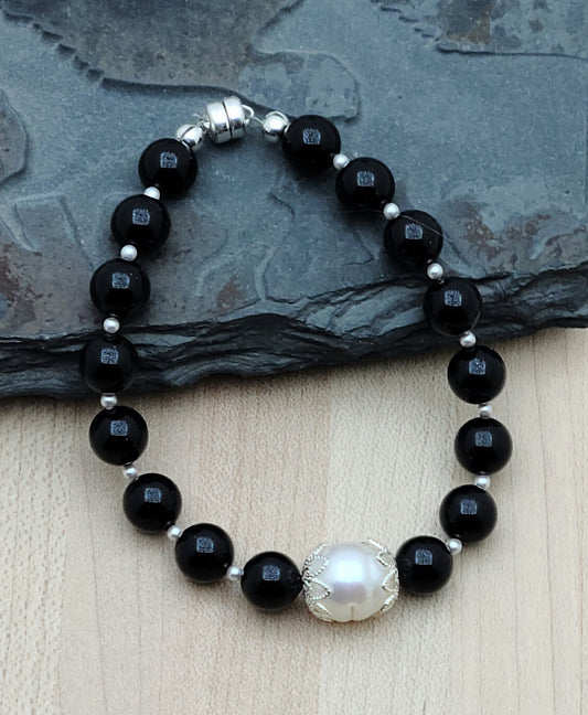 Indulge in luxury with our Black & FW Pearl Bracelet. The combination of black crystal pearls and a large white baroque freshwater pearl creates an elegant and exclusive piece that will elevate any outfit. Magnetic clasp