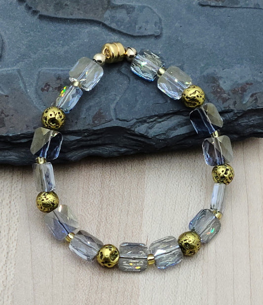 Be captivated by the elegant beauty of my Blue & Gold Bracelet. Featuring stunning square crystals with a subtle gold hue, this bracelet is accented perfectly with gold plated lava stone.