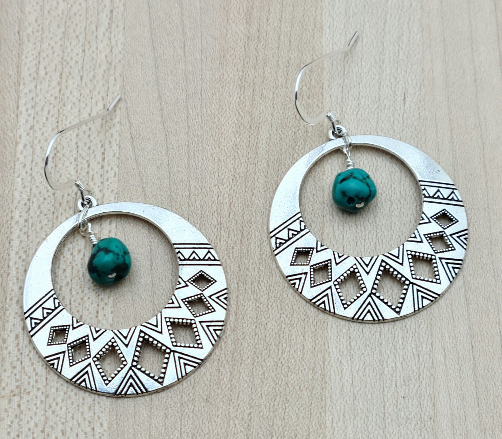 Tribal designed hoops host real Turquoise nuggets in these Earrings with sterling silver fish hook earwires.