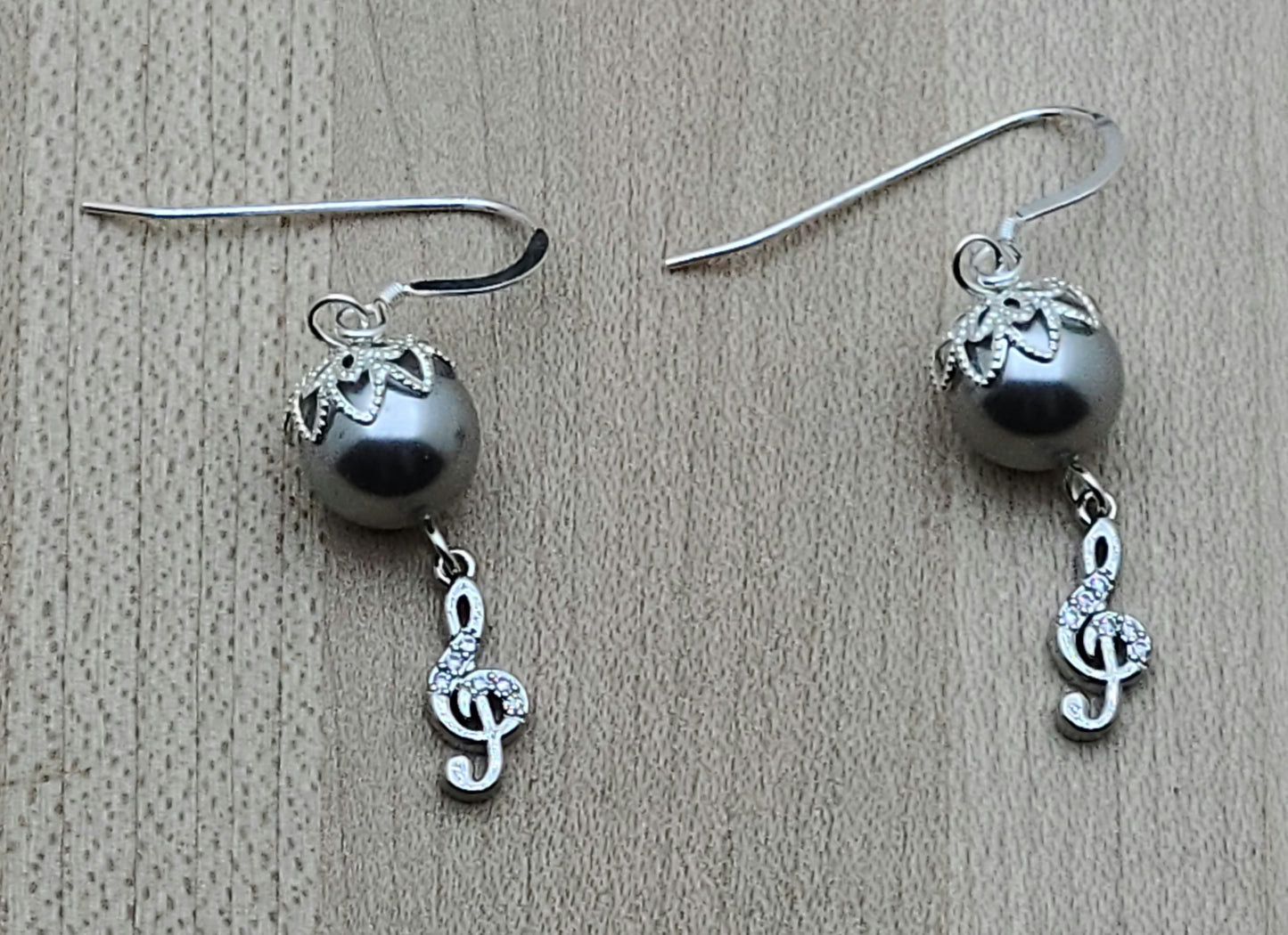 Sparkle with your love of music! Sterling silver & cubic zirconia treble clefs catch the light, as do the bead caps on the silver crystal pearls from which they are suspended!
Lovely & lightweight!
