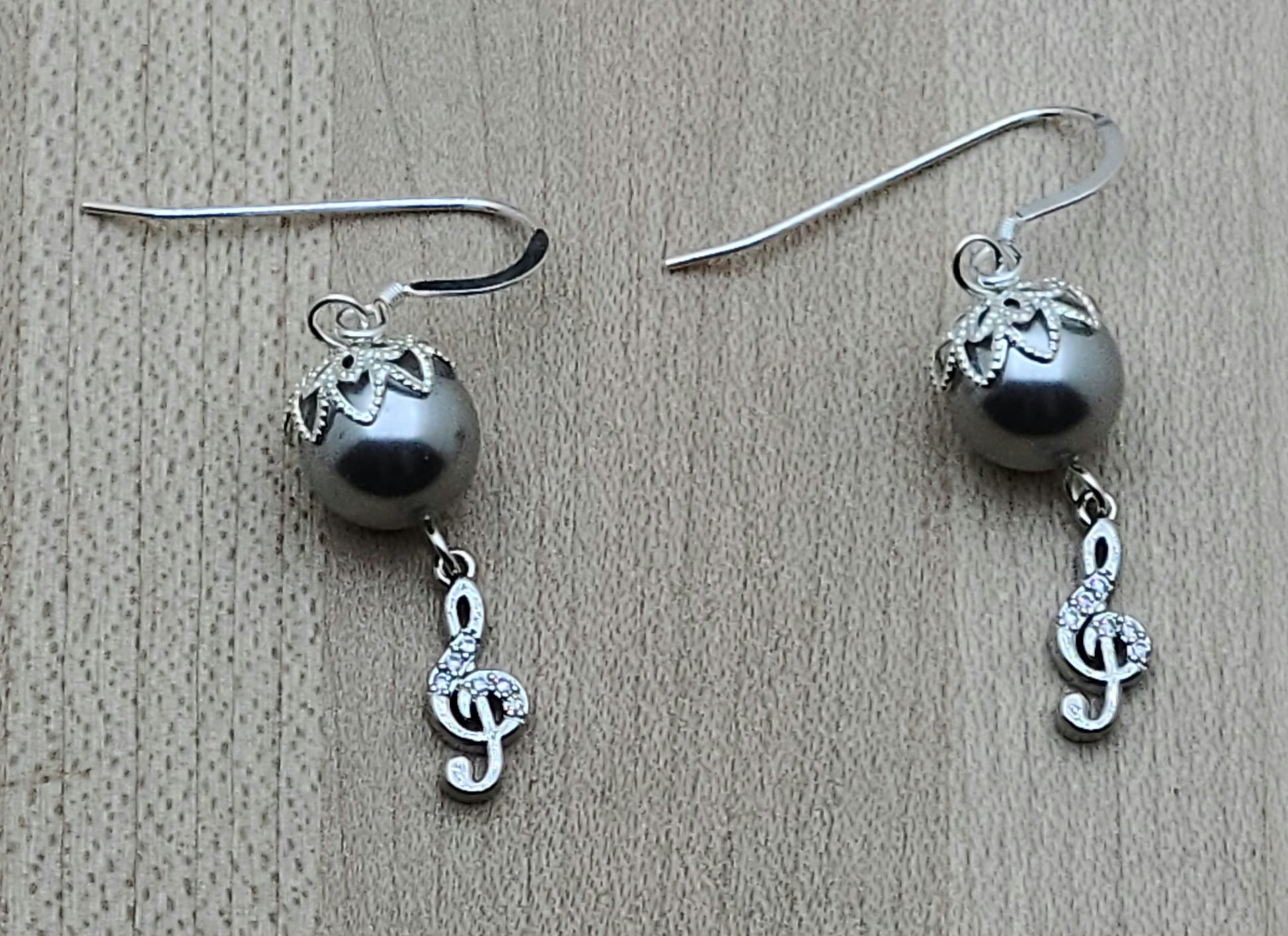 Sparkle with your love of music! Sterling silver & cubic zirconia treble clefs catch the light, as do the bead caps on the silver crystal pearls from which they are suspended!
Lovely & lightweight!