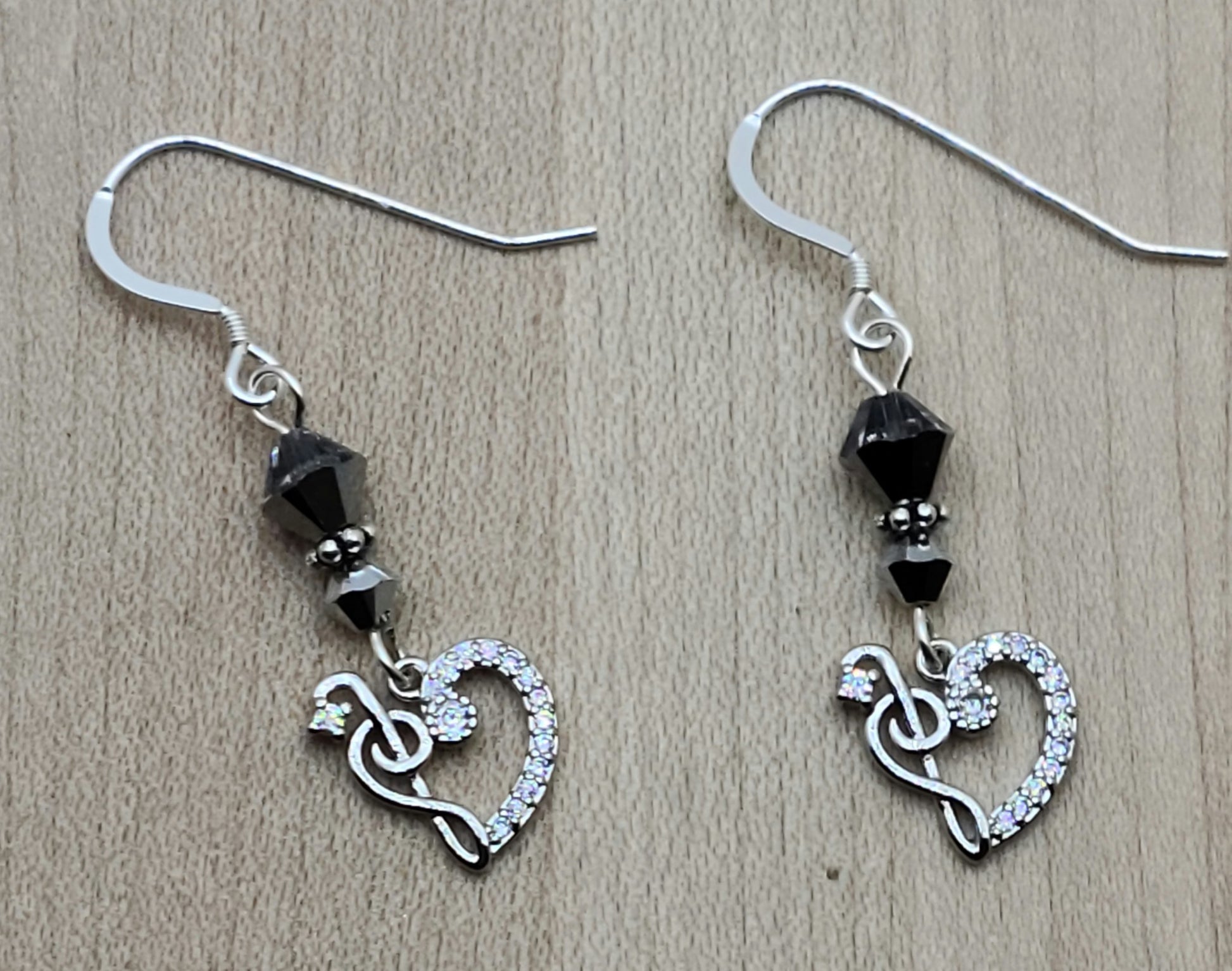 Sparkle with your love of music! Sterling silver & cubic zirconia treble clefs and bass clefs join to form a delightful heart & catch the light, as do the the crystals from which they are suspended!
