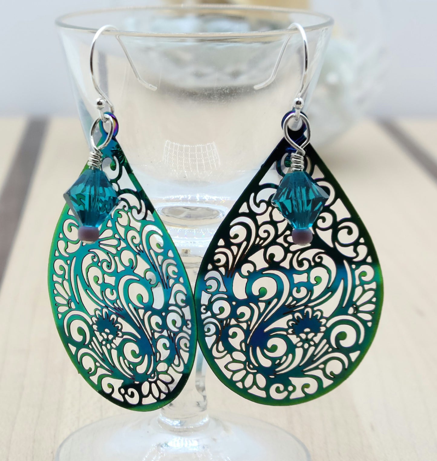 These incredibly lightweight teal electroplated stainless steel teardrops have been laser cut with a swirling & intricate design. I added a crystal ornament 'bling' element.
As the light catches these fun earrings, you'll also see a hint of purple!