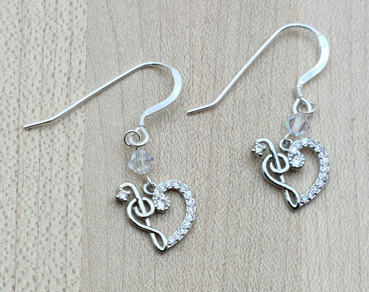 Sparkle with your love of music! Sterling silver &amp; cubic zirconia treble clefs and bass clefs join to form a delightful heart and catch the light, as do the the crystals* from which they are suspended!
Lovely &amp; lightweight!