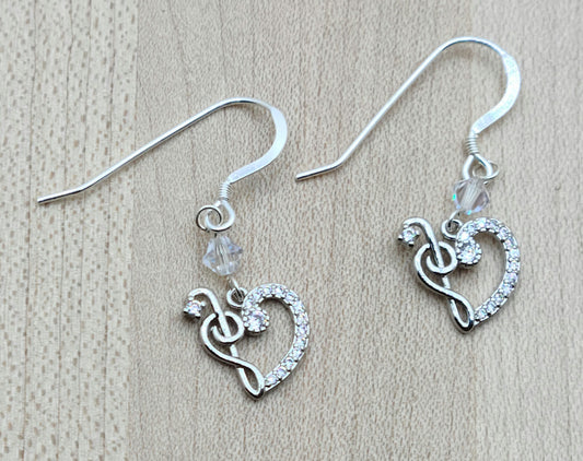 Sparkle with your love of music! Sterling silver &amp; cubic zirconia treble clefs and bass clefs join to form a delightful heart and catch the light, as do the the crystals* from which they are suspended!
Lovely &amp; lightweight!