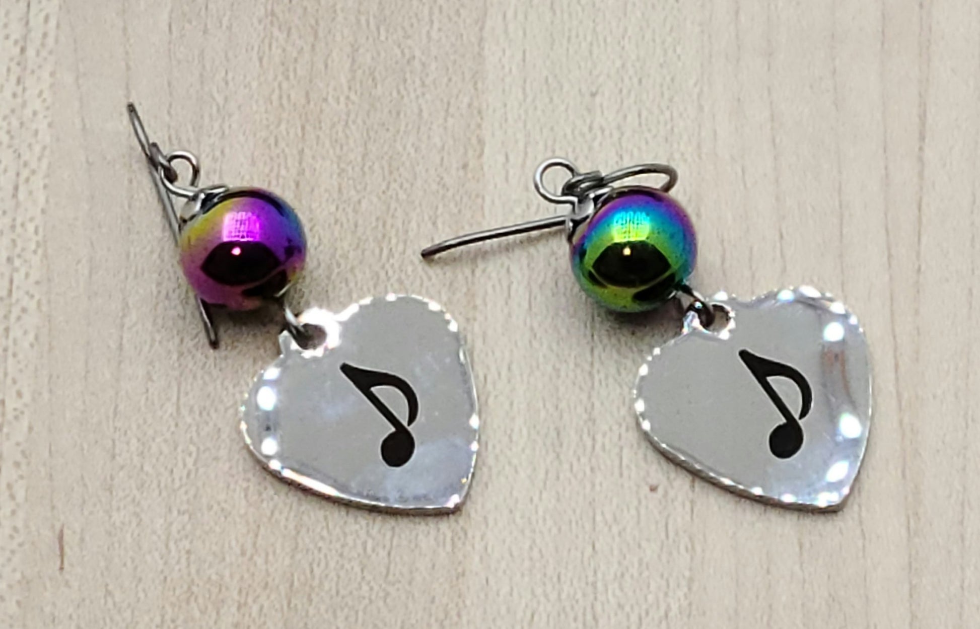 Love music? Play a group? Then these stainless steel hearts displaying an 8th note are for you! For added interest they hang from hematite beads electroplated in rainbow colors!
1 3/4" with niobium (considered hypoallergenic) fish hook earwires