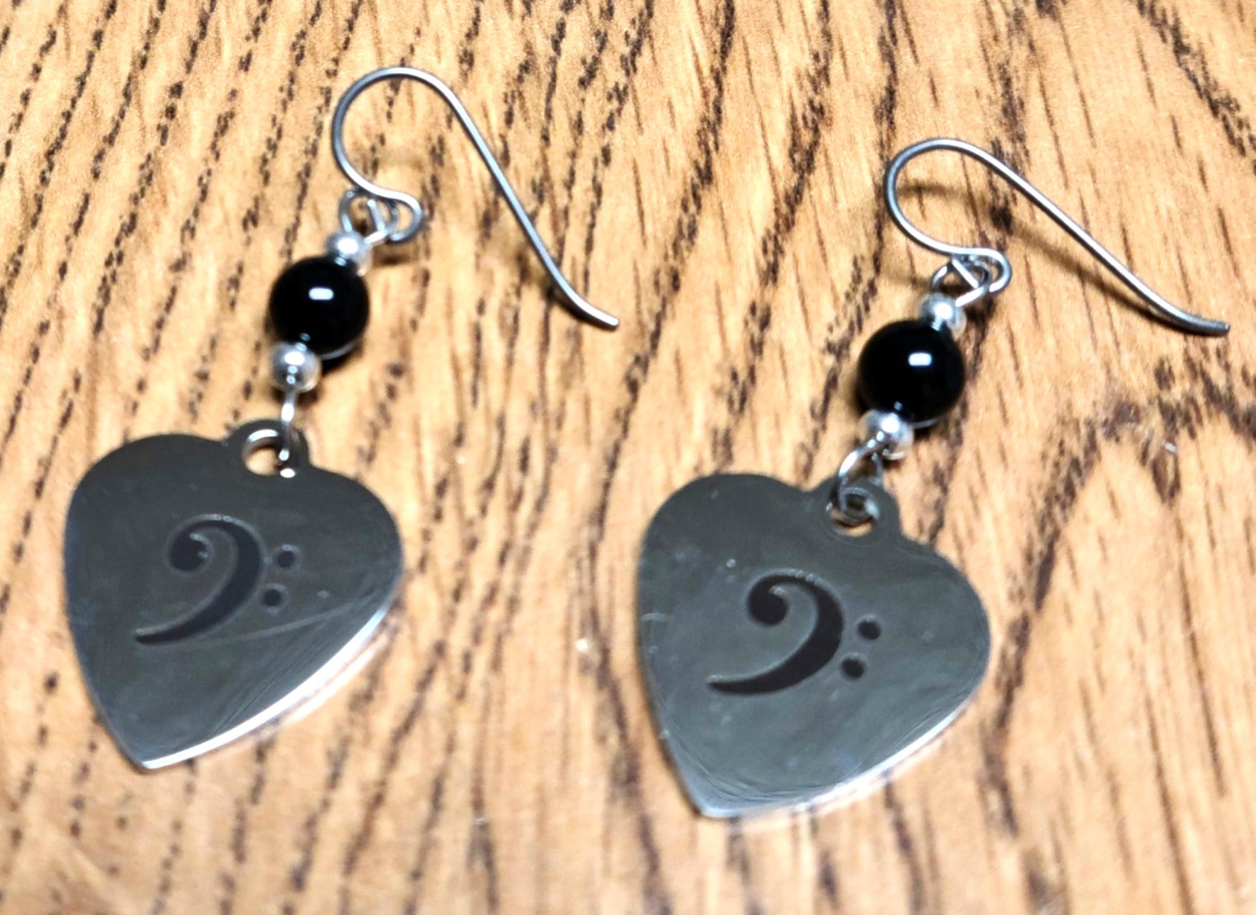 Love music? Play a bass clef instrument? Then these stainless steel hearts displaying a bass clef are for you! For added interest they hang from black crystal pearls.
1 3/4" with niobium (considered hypoallergenic) fish hook earwires