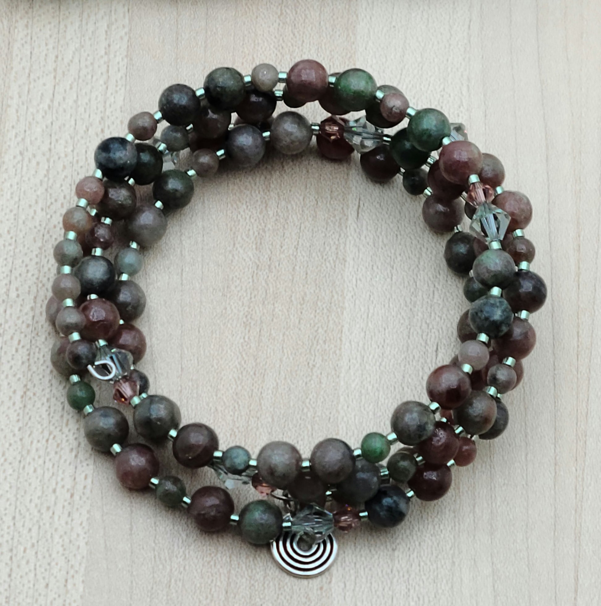The mixed, earthy color palette of burgundy, forest green, black, & white swirls in Kashgar garnet are paired with pale green & vintage rose crystals & green Miyuki delica to create a lovely 4 row memory wire bracelet.