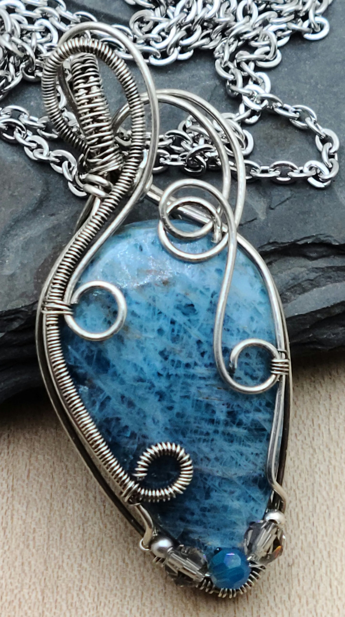 Lovely blue apatite teardrop cabochon framed with antique silver filled woven wire in swirling patterns.