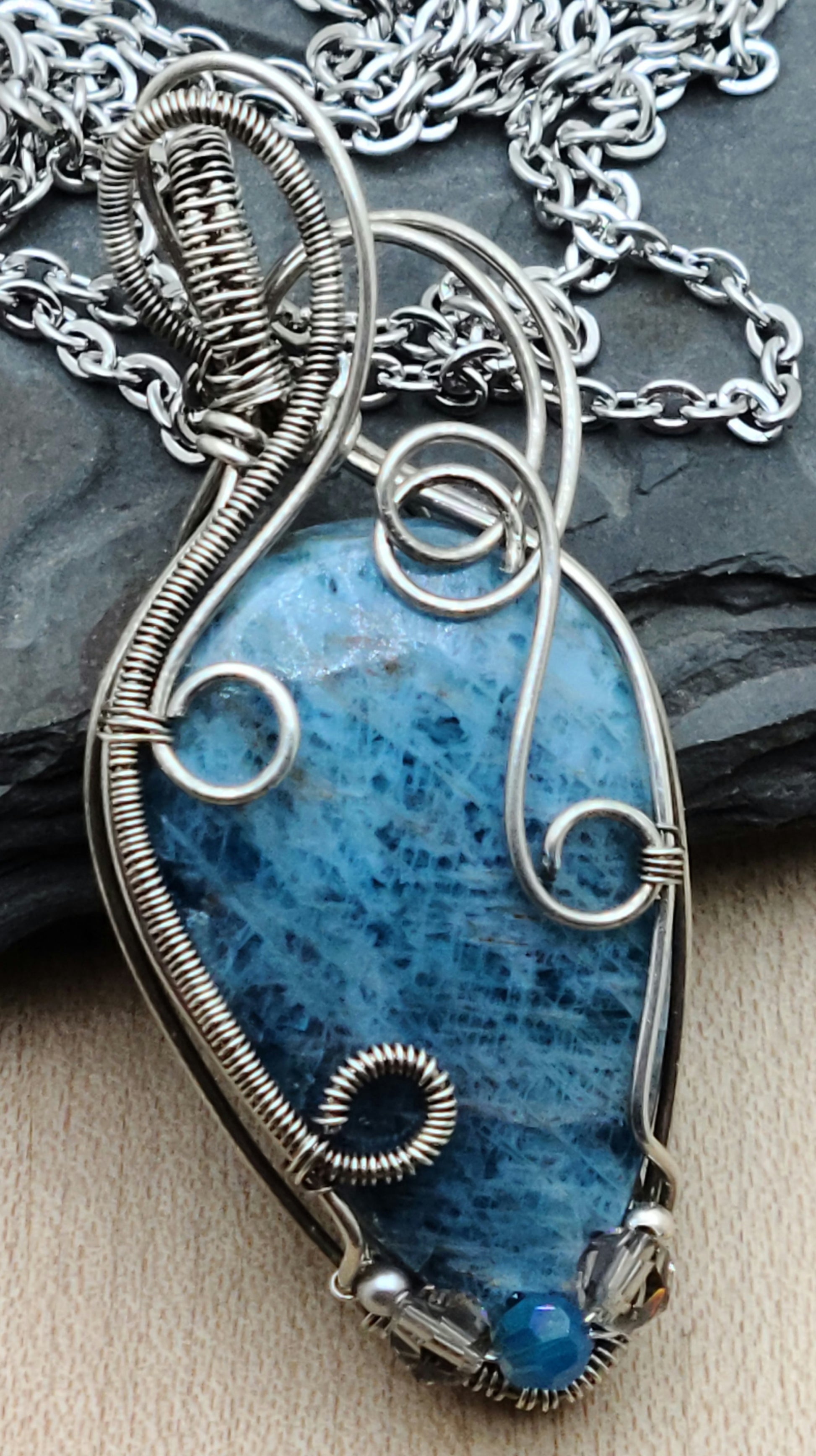 Lovely blue apatite teardrop cabochon framed with antique silver filled woven wire in swirling patterns.