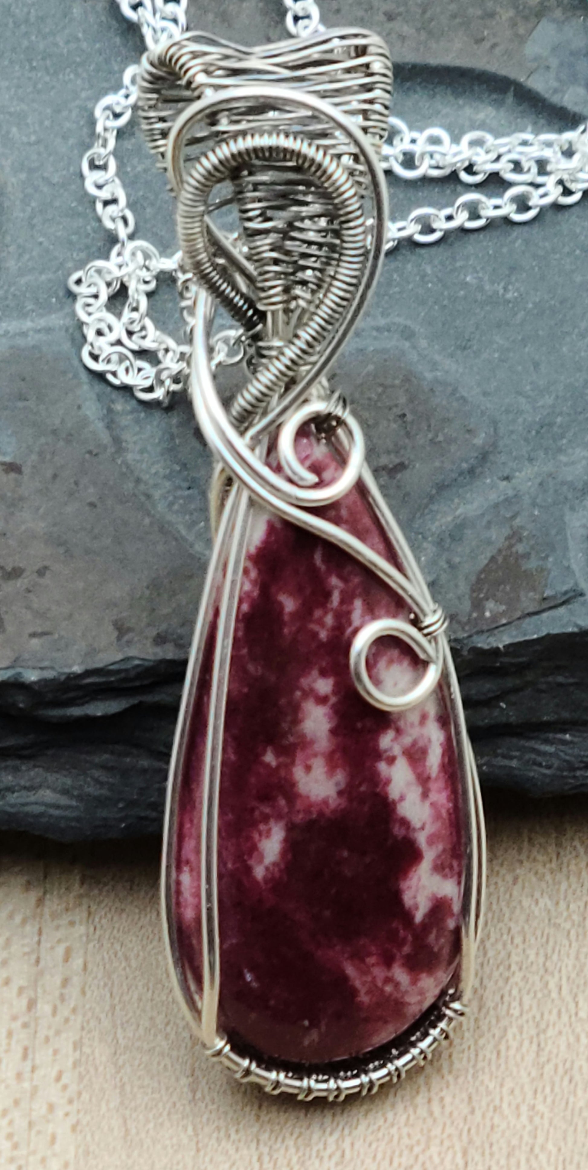 Pink thulite is a stone of the heart chakra, said to open pathways to unconditional love, compassion, and kindness. This pendant features expertly woven silver filled and antiqued silver filled wire—much more silver than plating—carefully sculpted into an design that showcases the stone's gentle light-to-dark pink gradations.