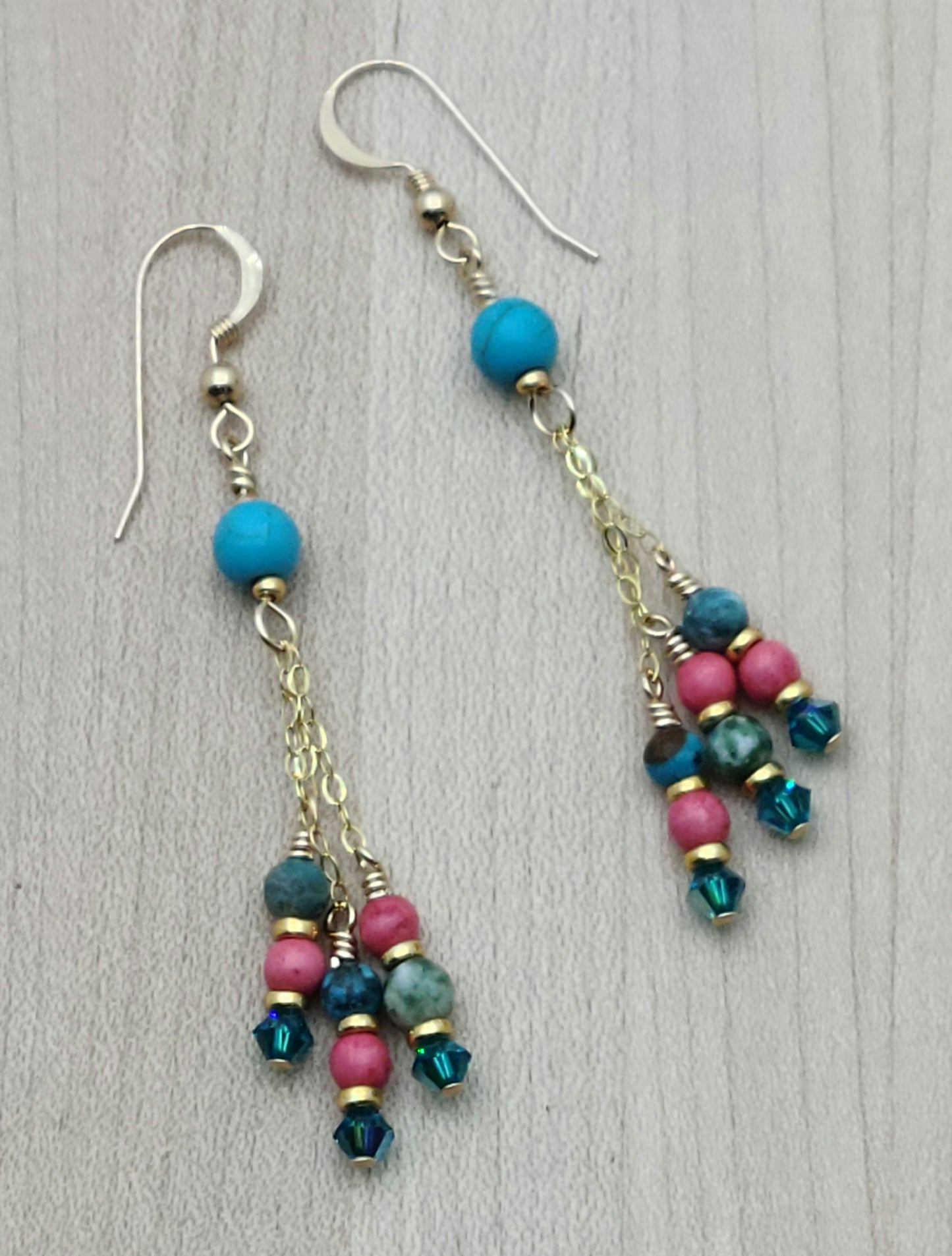 Fun and vibrant, these dangle earrings captures attention with bright, happy colors of turquoise, bright pink, green, & gold.