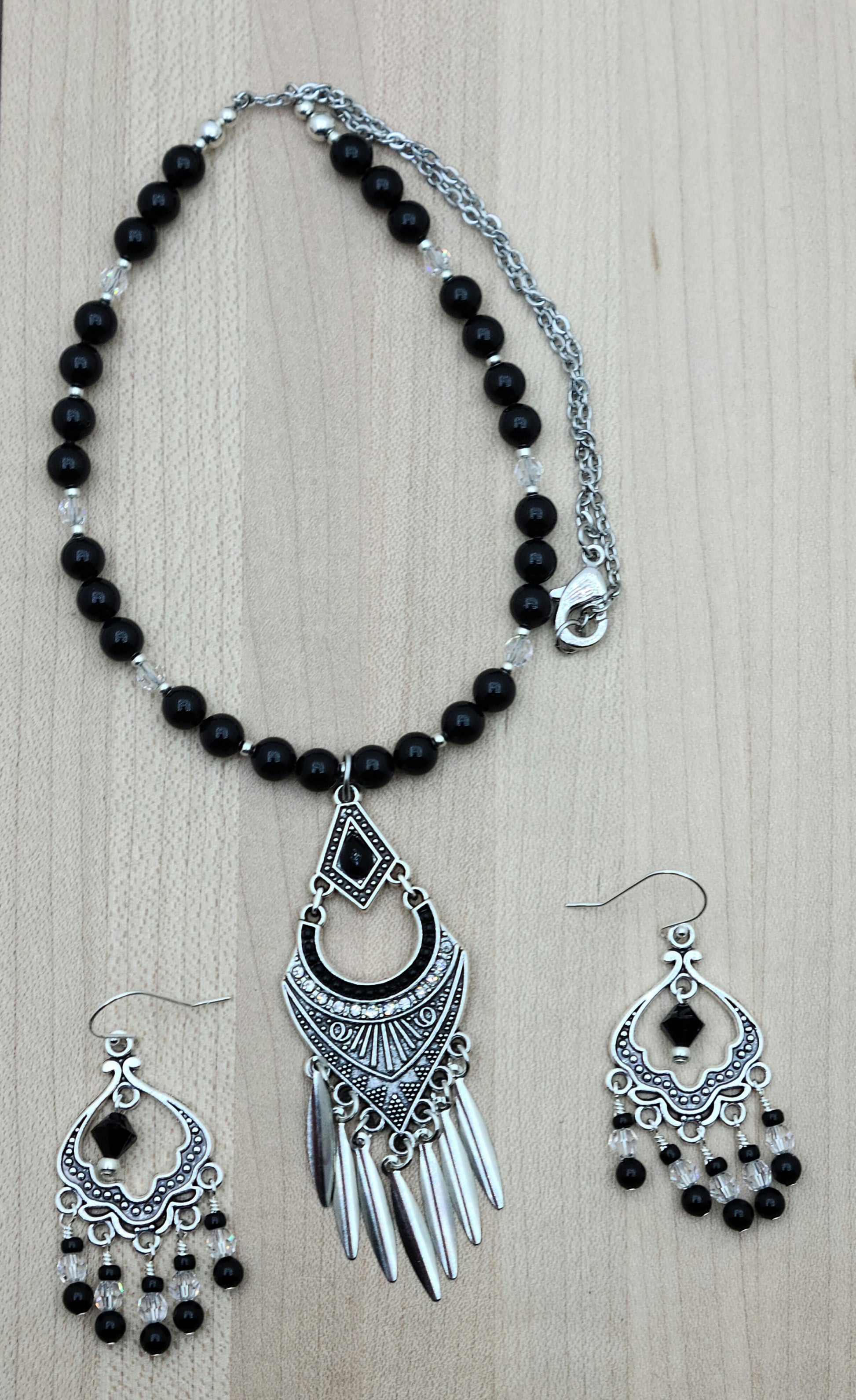 An intricate & fancy lead-free pewter pendant features a black stone & pewter blade fringe.  Also pewter & crystal chandelier earrings