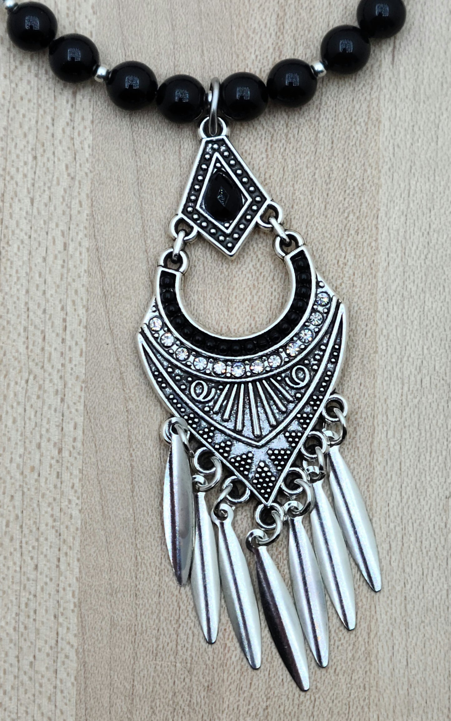 An intricate & fancy lead-free pewter pendant features a black stone & pewter blade fringe.  