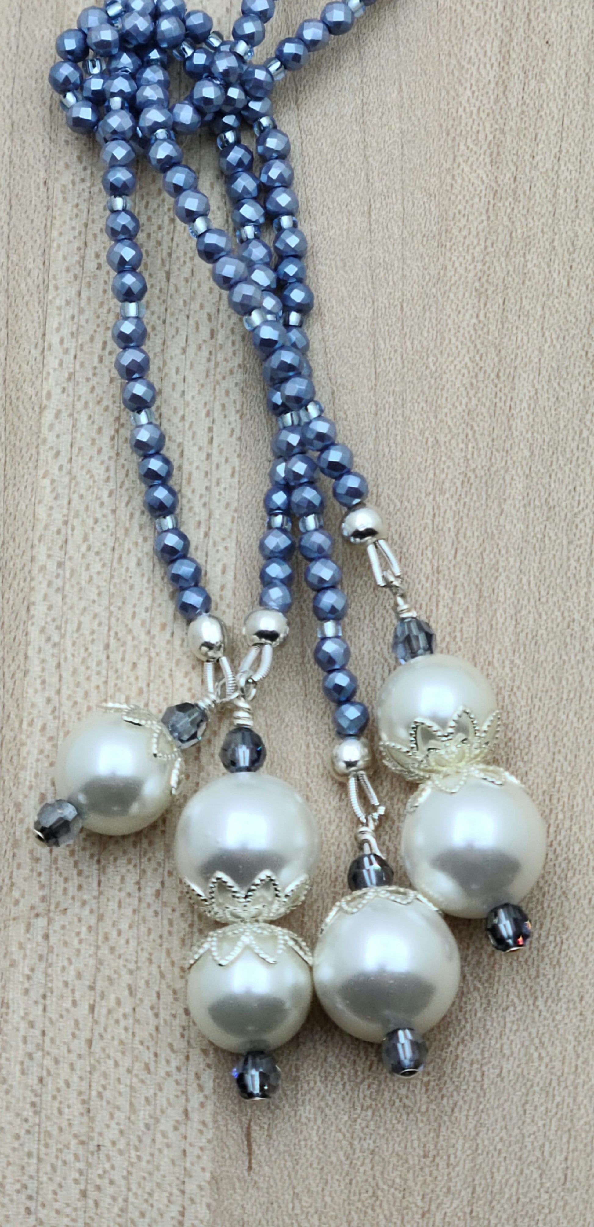 close up of shell pearls dangles on blue lariat necklace