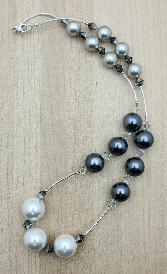 Large light silver, dark silver, and white shell pearls shine alongside liquid silver accents and sparkling crystals in this elegant matching set.