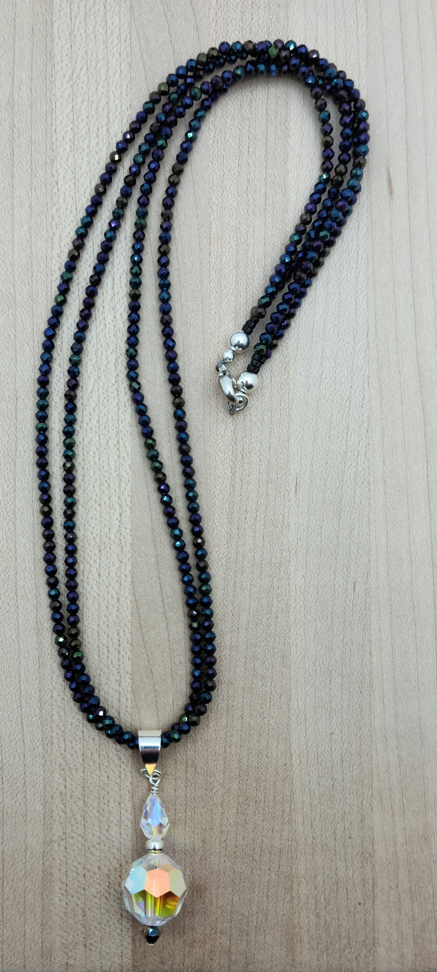 You'll be drawn to the shimmery aurora borealis coating of these tiny black spinel stones and that shimmer continues in the aurora borealis coating of the crystal pendant.