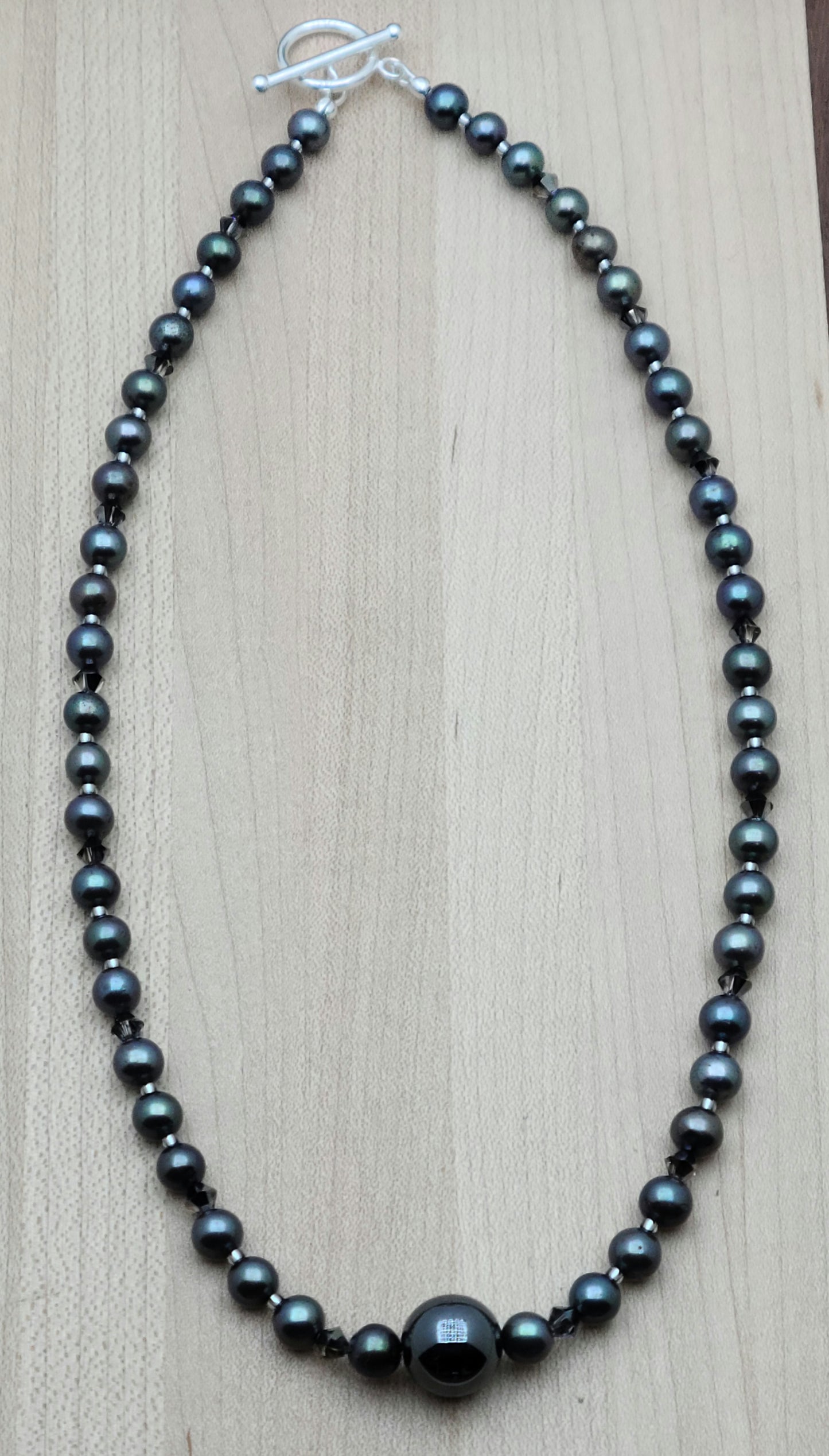 With a dark bluish grey cast, these black freshwater pearls look great with the single, large shiny grey hematite statement bead and silver night crystals!
