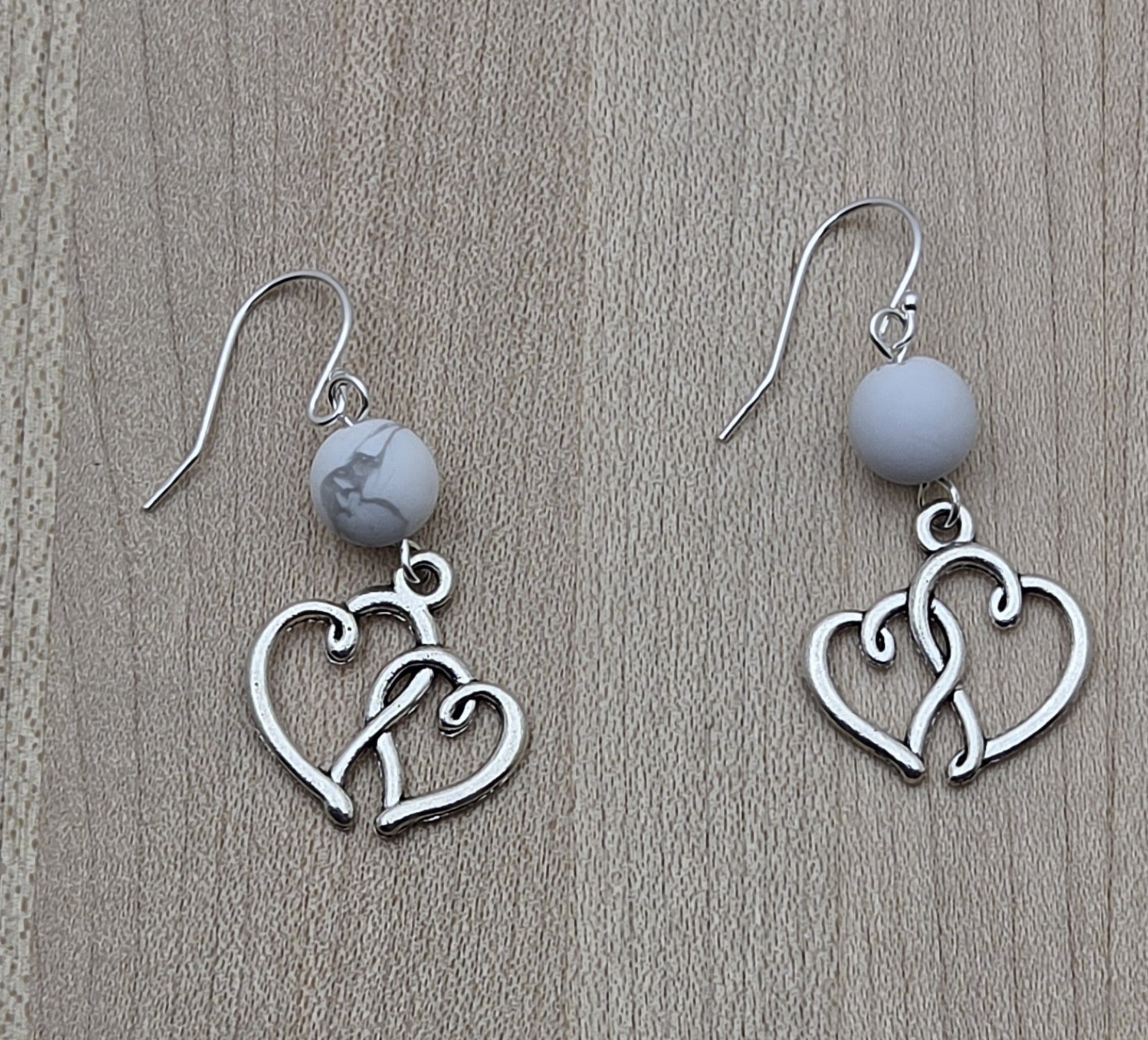 These lead-free pewter entwined heart earrings are simple, adorable, and extremely lightweight. A fun look without the weight! The hearts hang from white howlite beads for a neutral color profile.