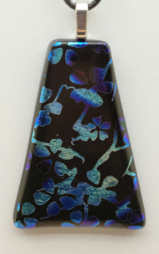 This handcrafted fused glass pendant features stunning etched dichroic glass, showcasing intricate blue and silver blossoms against a striking black background.