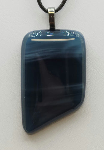 Swirls of deep slate blue dance across this stunning fused glass pendant.