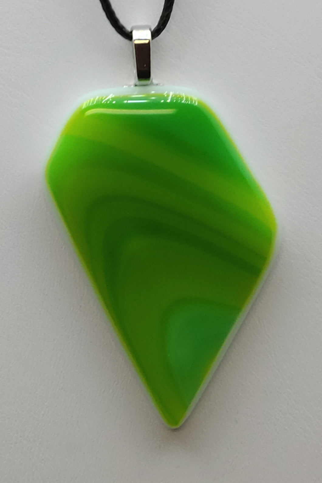 Add a fun twist to your outfit with our Olive Swirl Fused Glass Pendant. The playful mixture of olive green, spring green, and a hint of aqua will surely catch everyone's attention.