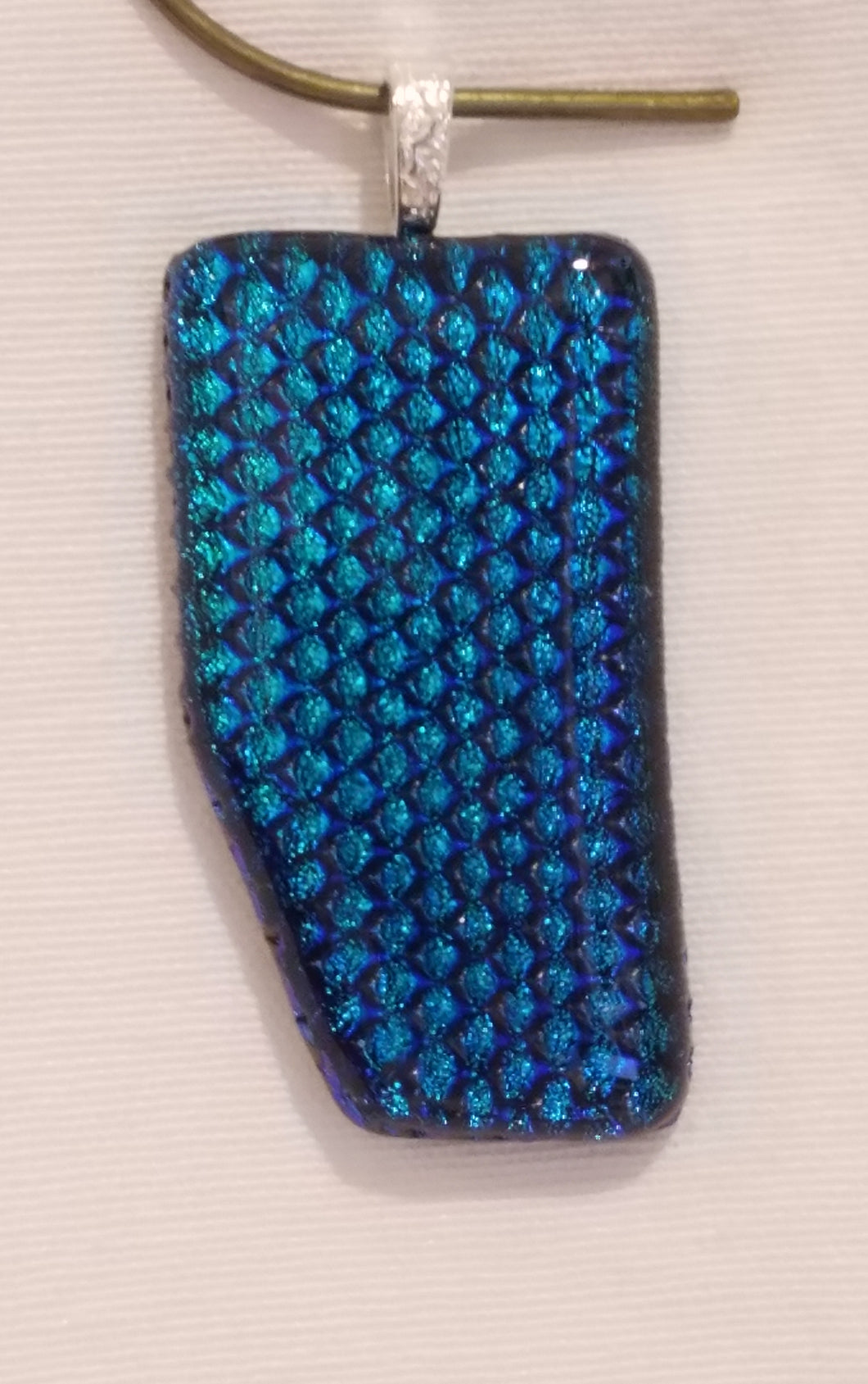 This pendant is a heavily texture, but capped dichroic which leans towards the blue spectrum of teal.