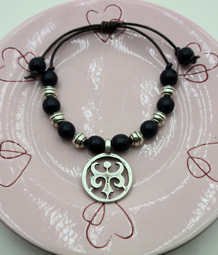 Wonderful casual attire leather slider bracelet silver pewter fleur-de-lis flanked black wood beads and silver plated ceramic beads.