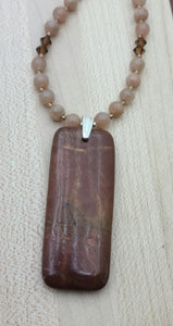 In this necklace a deeply rust red Red Creek jasper pendant is suspended from complimentary pale peach moonstone beads & accented by dark topaz crystals*.