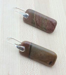 In these earrings, deeply rust red Red Creek jasper pendants is suspended sterling silver fish hooks