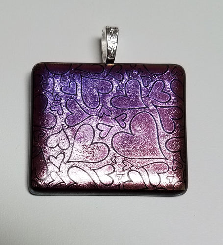 An elegant piece with hearts etched onto purple hues dichroic glass