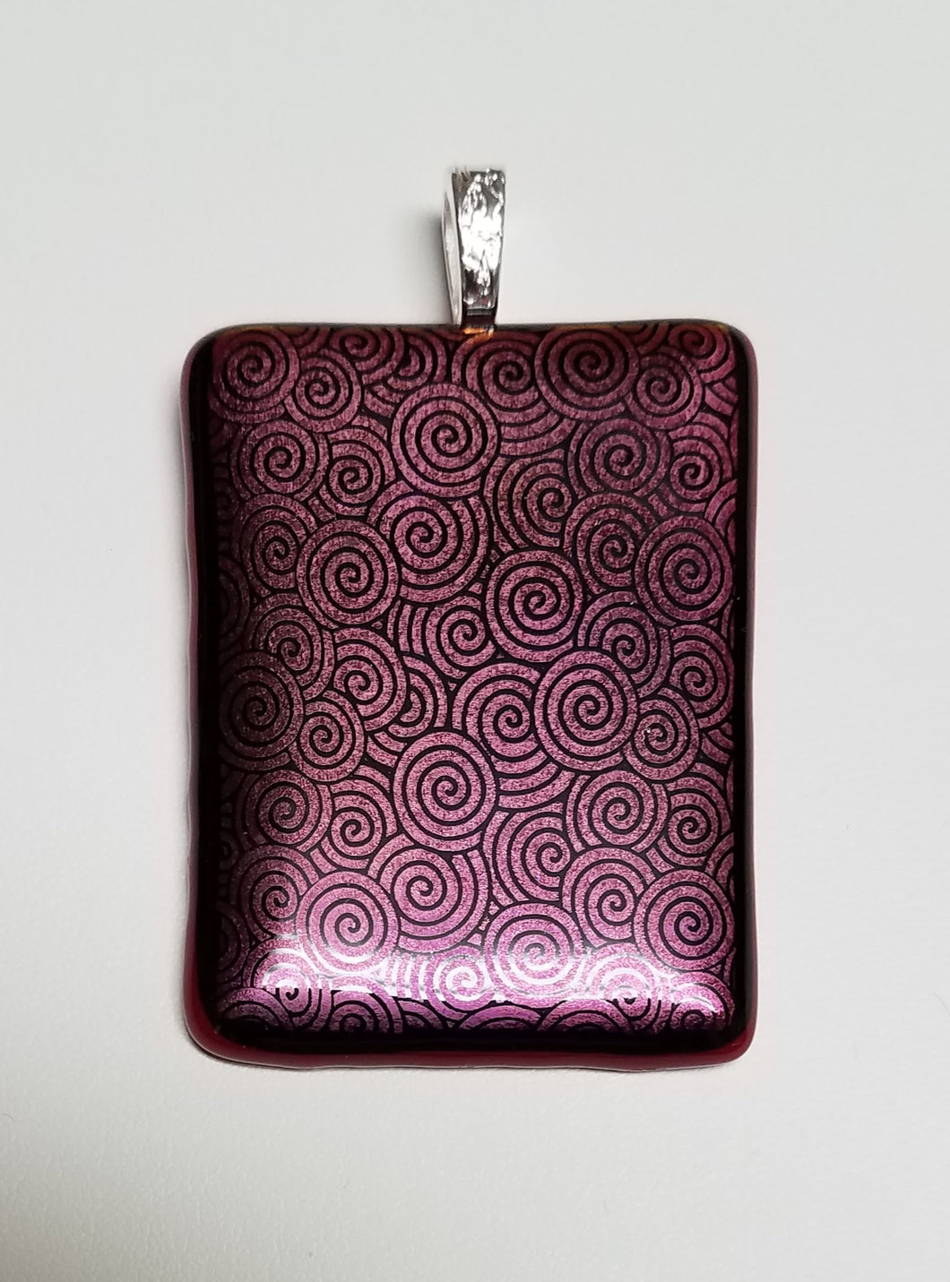Black swirls are etched onto red dichroic glass